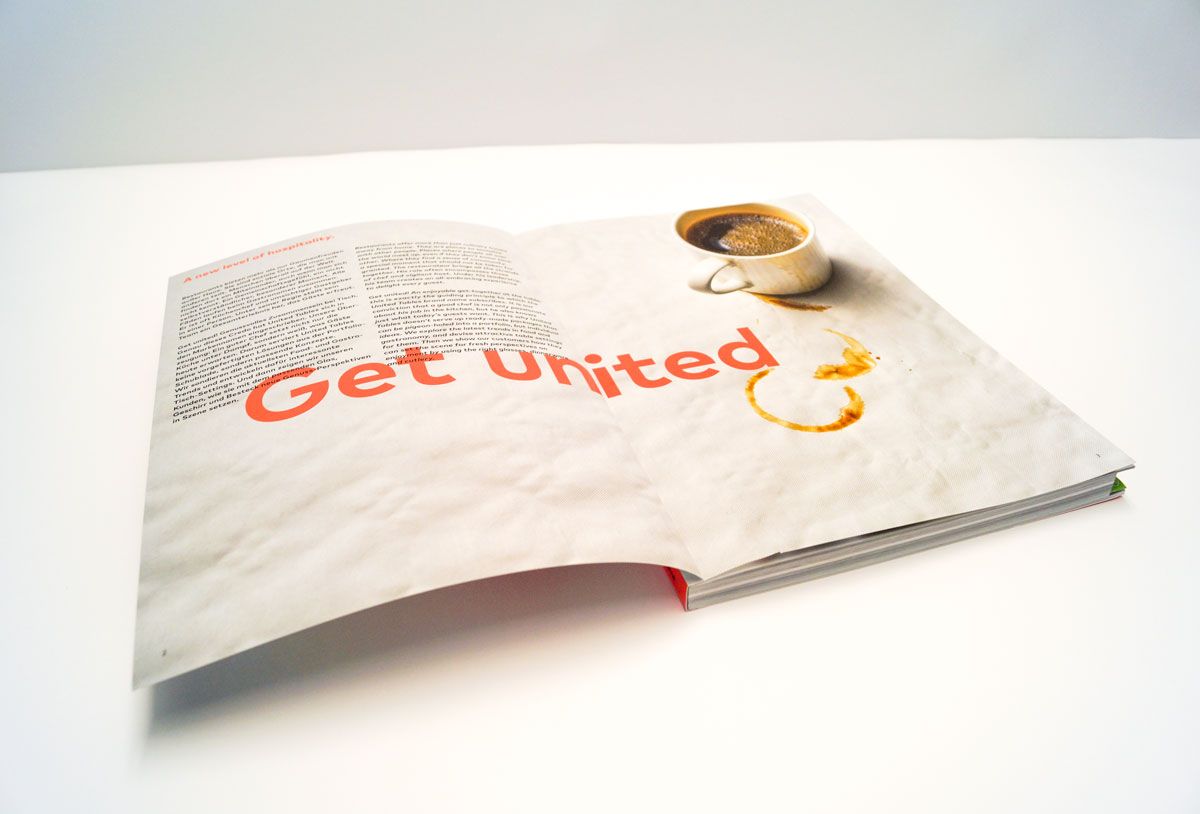 aufgeklappte Softcover-Broschüre, Schriftzug und Bild Kaffeetasse