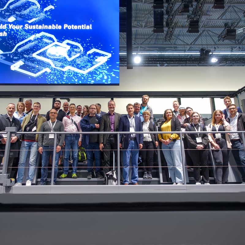 Gruppenbild: die Mitarbeitenden von Aumüller Druck auf einer Druckmaschine