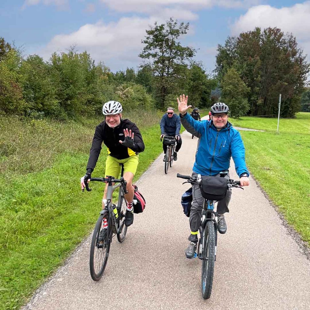 AUMÜLLER-Radtour 2025 2 Drei Radfahrer, wo einer wingt.