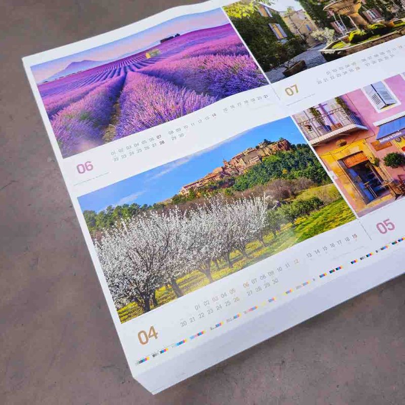 Ein Stapel frisch gedruckter Kalender, auf denen Landschaften abgebildet sind