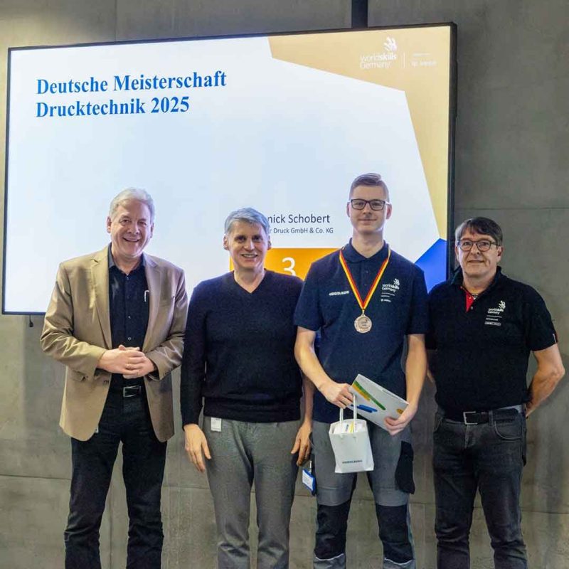 Gruppenbild: mit Yannik und drei weiteren Männern vor einem Bildschirm.