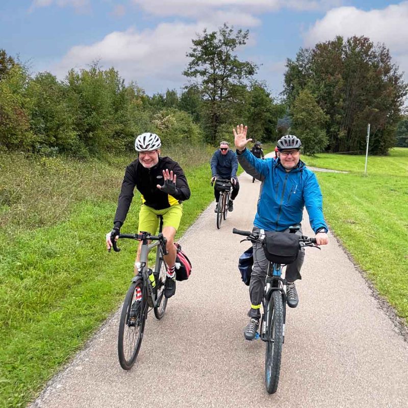 Drei Radfahrer, wo einer wingt.